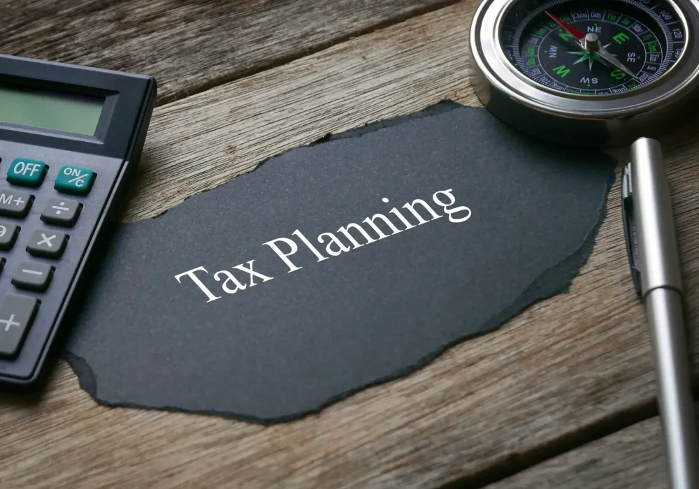 Compass,calculator,pen and a piece of black paper written with Tax Planning on wooden background. Compass,calculator,pen and a piece of black paper written with Tax Planning on wooden background.